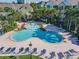 Gathering-friendly community pool with splash zone surrounded by lounge chairs and tropical landscaping at 3002 Bonfire Beach Dr # 202, Kissimmee, FL 34746