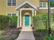 Charming front entrance with a teal front door, white columns, and lush landscaping at 3002 Bonfire Beach Dr # 202, Kissimmee, FL 34746
