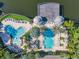 Aerial view of community pools and deck featuring lounge chairs, umbrellas, lush landscaping and waterfront pier at 3002 Bonfire Beach Dr # 202, Kissimmee, FL 34746