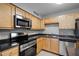 Kitchen with stainless appliances, wood cabinets, and black countertops, complemented by the easy-to-clean tiled floors at 305 Lakepointe Dr # 103, Altamonte Springs, FL 32701