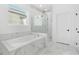 Bright bathroom featuring a soaking tub, a glass shower, and white marble tile throughout at 3351 Pine Timber Pt, Oviedo, FL 32765