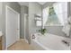 Bright bathroom with a white soaking tub, clear glass shower, and decorative window at 34000 Fortunado St, Sorrento, FL 32776