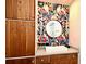 Stylish bathroom boasts wood cabinets, floral wallpaper, a round mirror, and a modern sink at 3714 Virginia Dr, Orlando, FL 32803
