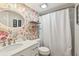 Stylish bathroom featuring floral wallpaper, shower with curtain, and decorative oval mirror at 3800 Saxon Dr # 19B, New Smyrna Beach, FL 32169