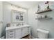 Bright bathroom with white vanity, decorative mirror, shelving and ample lighting at 3800 Saxon Dr # 19B, New Smyrna Beach, FL 32169