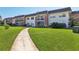A view of the condo complex exterior with manicured lawn and concrete sidewalk leading to the building at 3800 Saxon Dr # 19B, New Smyrna Beach, FL 32169