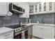 Modern kitchen features stainless steel appliances, sleek gray backsplash and white cabinets at 3800 Saxon Dr # 19B, New Smyrna Beach, FL 32169