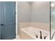 Bright bathroom featuring a soaking tub with modern, dark fixtures and a stylish blue door at 4210 Sunset Preserve Blvd, Orlando, FL 32820