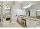 Bright primary bathroom featuring double sinks, granite countertops, vanity area, and tiled floor leading to the bedroom at 442 Devon Pl, Lake Mary, FL 32746