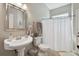 Bright bathroom with pedestal sink, large mirror, and shower featuring neutral-toned decor at 442 Devon Pl, Lake Mary, FL 32746