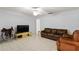 Spacious living room with tile flooring, ceiling fan, leather sofa, and modern entertainment center at 4913 E Wind St, Orlando, FL 32812