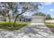 Inviting single-story home featuring lush green lawn, mature trees, and spacious driveway at 607 S Glencoe Rd, New Smyrna Beach, FL 32168