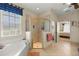 Bright bathroom featuring a soaking tub, glass-enclosed shower, and a view to the Primary bedroom at 8712 Sw 83Rd Cir, Ocala, FL 34481