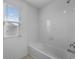 Clean white bathroom with a built-in tub, tiled walls, and natural light from the window at 1171 Lone Palm Way, St Cloud, FL 34771