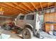 Open garage with exposed wood beams and vehicle under repair, revealing potential for mechanic or hobbyist at 11811 Kijik Trl, Groveland, FL 34736