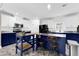 Well-lit kitchen with white and navy cabinets, stainless steel countertops and appliances, and a butcher block island with seating at 11811 Kijik Trl, Groveland, FL 34736