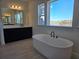 Spa bathroom with a soaking tub next to a window and dual sinks with black hardware at 13217 Tollcross Way, Winter Garden, FL 34787