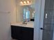 Modern bathroom featuring a black vanity, white countertop, a large mirror, and open shelving for ample storage at 13217 Tollcross Way, Winter Garden, FL 34787