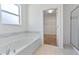 Bright bathroom featuring a soaking tub, tiled floors, and glass shower door at 1407 Leitrim Loop, Apopka, FL 32703