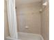 Neutral-tiled bath and shower feature updated fixtures and a clean white shower curtain at 145 N Halifax Ave # 601, Daytona Beach, FL 32118