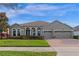 Charming home featuring arched entryways, a well-maintained lawn, and a spacious three-car garage at 15993 Johns Lake Overlook Dr, Winter Garden, FL 34787