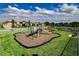 Community playground with green and tan play structures on a mulch surface surrounded by grass and fencing at 15993 Johns Lake Overlook Dr, Winter Garden, FL 34787