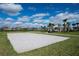 Sandy volleyball court surrounded by green grass, palm trees, and well maintained landscaping at 15993 Johns Lake Overlook Dr, Winter Garden, FL 34787