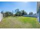 The grassy backyard is defined by a white fence and dotted with young trees at 1671 Spray Ter, St Cloud, FL 34771