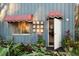 Inviting home entrance featuring a decorative awning, unique wall art, and lush greenery at 2614 W Ponkan Rd, Apopka, FL 32712