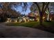 Exterior shot of a well-maintained home with a lush front lawn, mature trees, and evening lighting at 2614 W Ponkan Rd, Apopka, FL 32712