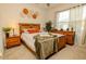 Bright bedroom featuring a wood frame bed, wooden nightstands, and decorative wall art for a warm, inviting atmosphere at 3332 Logan Berry Dr, Mount Dora, FL 32757