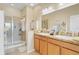 Well-lit bathroom featuring a double sink vanity and a glass-enclosed shower at 3640 Solana Cir # A, Clermont, FL 34711