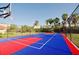 Outdoor basketball court featuring vibrant red and blue surfaces, surrounded by fencing, landscaping and palm trees at 5000 Cayview Ave # 10108, Orlando, FL 32819