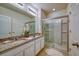 Well-lit bathroom featuring double sinks, granite countertop, and a glass-enclosed shower at 6090 Broad Oak Dr, Davenport, FL 33837