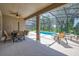 Covered patio with an outdoor seating area, overlooking a screened-in pool and lush landscaping at 6090 Broad Oak Dr, Davenport, FL 33837