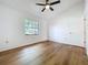 Bedroom with wood-look floors, ceiling fan, and large window at 10238 Summit Square Dr, Leesburg, FL 34788