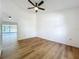 Bright bedroom with fan, wood-look flooring, and view of the screened patio at 10238 Summit Square Dr, Leesburg, FL 34788