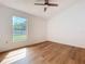 Bright bedroom features wood-look floors, ceiling fan, and a backyard view at 10238 Summit Square Dr, Leesburg, FL 34788