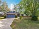 Charming single-story home featuring a blue two-car garage and a well-manicured front yard with mature trees at 10238 Summit Square Dr, Leesburg, FL 34788