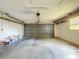 A spacious garage with a concrete floor, and a gray door providing ample space for storage and vehicles at 10238 Summit Square Dr, Leesburg, FL 34788