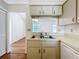 Efficient kitchen featuring a double stainless steel sink, white dishwasher, and a pass-through to the living area at 10238 Summit Square Dr, Leesburg, FL 34788