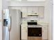 Well-lit kitchen with stainless steel refrigerator and stove, featuring white cabinets and ample countertop space at 10238 Summit Square Dr, Leesburg, FL 34788