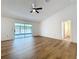 Main bedroom featuring wood-look floors, ceiling fan, and sliding glass doors to the enclosed lanai at 10238 Summit Square Dr, Leesburg, FL 34788