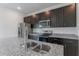 Modern kitchen featuring stainless steel appliances, dark cabinets, a granite countertop and a dual basin sink at 13220 Sw 85Th Pl, Ocala, FL 34473