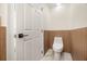 A compact bathroom featuring a toilet, wood paneling and a white door, with a minimalist design at 1531 Lake Baldwin Ln, Orlando, FL 32814