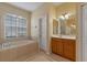 A bathroom with a bathtub under the window and a wooden vanity, with tile flooring at 1657 Cherry Ridge Dr, Lake Mary, FL 32746