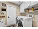 Bright laundry room with white appliances, cabinets, granite counters, and door to exterior at 1804 Wind Willow Rd, Belle Isle, FL 32809