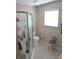 Neutral-toned bathroom features a shower, toilet, window, and seating at 419 Aldama Ave, Lady Lake, FL 32159