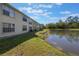 Apartment building overlooking a pond with lush greenery under a partly cloudy sky at 5007 Laguna Bay Cir # 31, Kissimmee, FL 34746