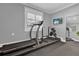 Well-equipped home exercise room with treadmill, weight rack, mirror, and natural light from the window at 5205 Saint Regis Pl, Belle Isle, FL 32812